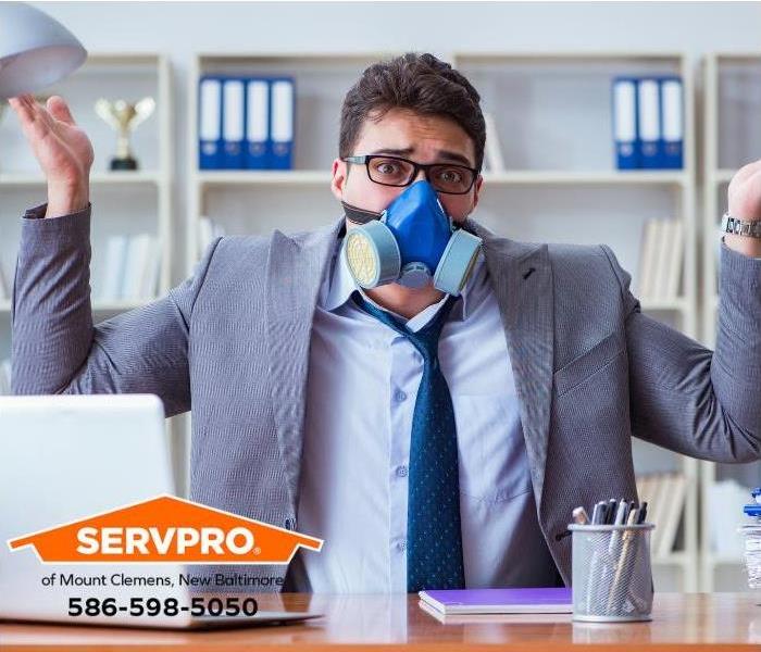 An employee is wearing a mask to avoid smelling a foul odor in his office.